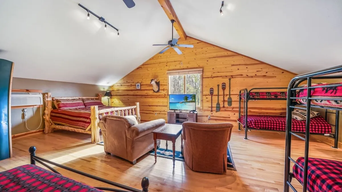 A family-friendly room with wooden bunk beds, a TV, wooden furniture, and a large window bringing in natural light. The scene is ready for movie nights, games, and relaxing family time.