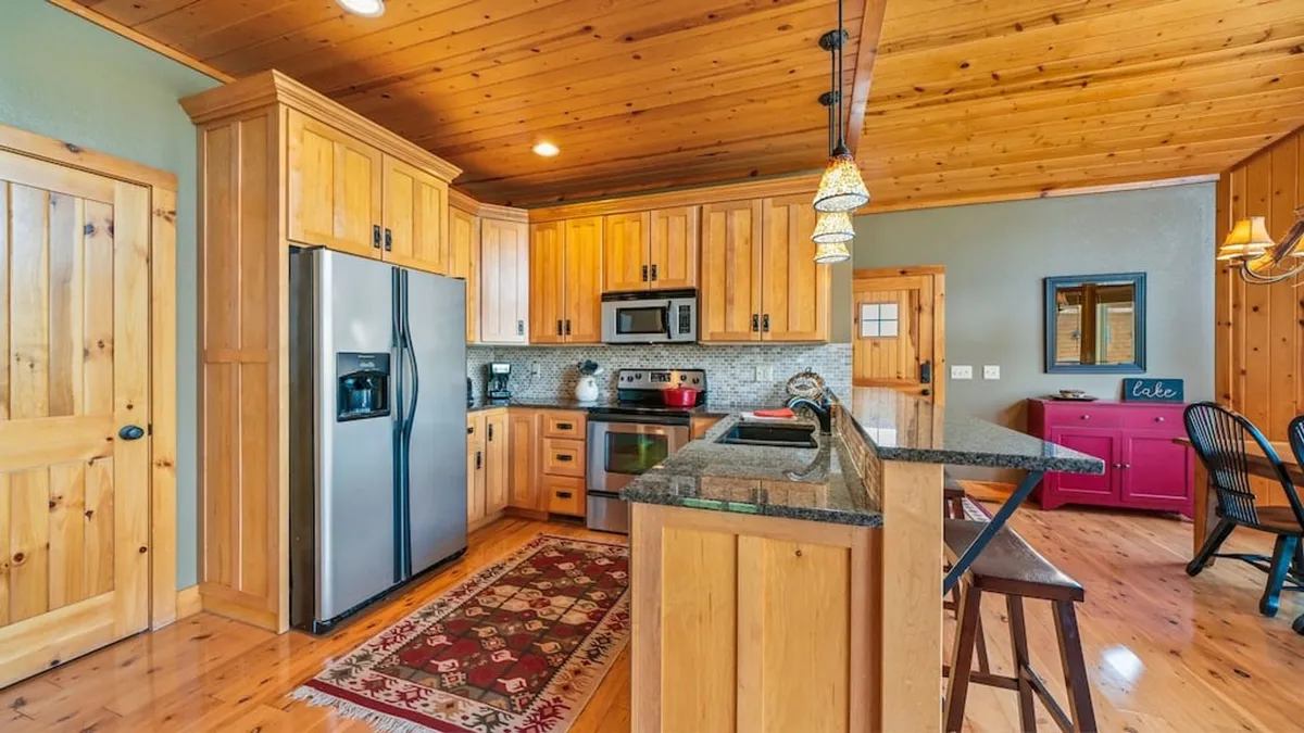 This image captures a well-appointed kitchen featuring a granite countertop, warm wood cabinetry, and stainless steel appliances. The decorative rug and welcoming layout suggest a space ideal for group meal prep, cooking together, and enjoying family traditions. The kitchen’s openness invites both cooking and socializing, making it the perfect heart of the home.