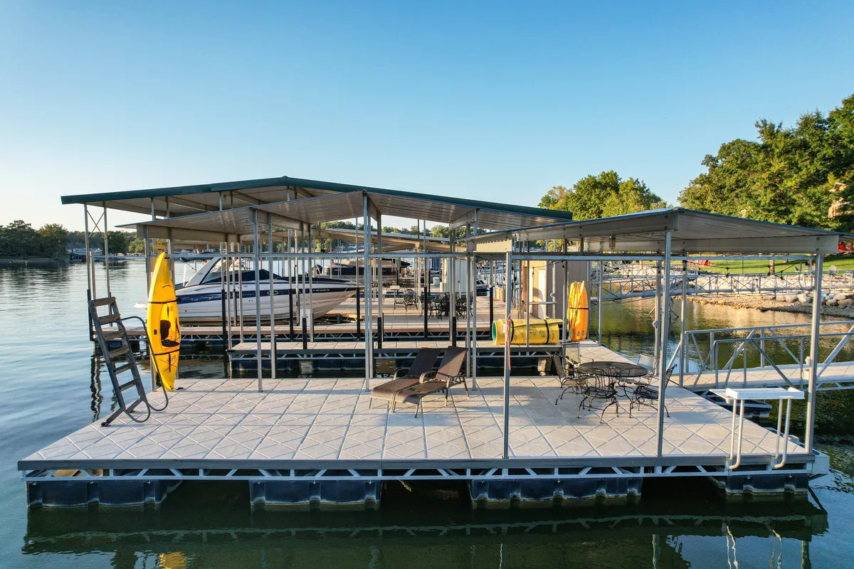 This inviting image shows a dock structure equipped with lounge chairs and a kayak, with several boats moored in the background. The tranquil water and comfortable seating create a leisurely lakeside atmosphere perfect for both adventure and relaxation.