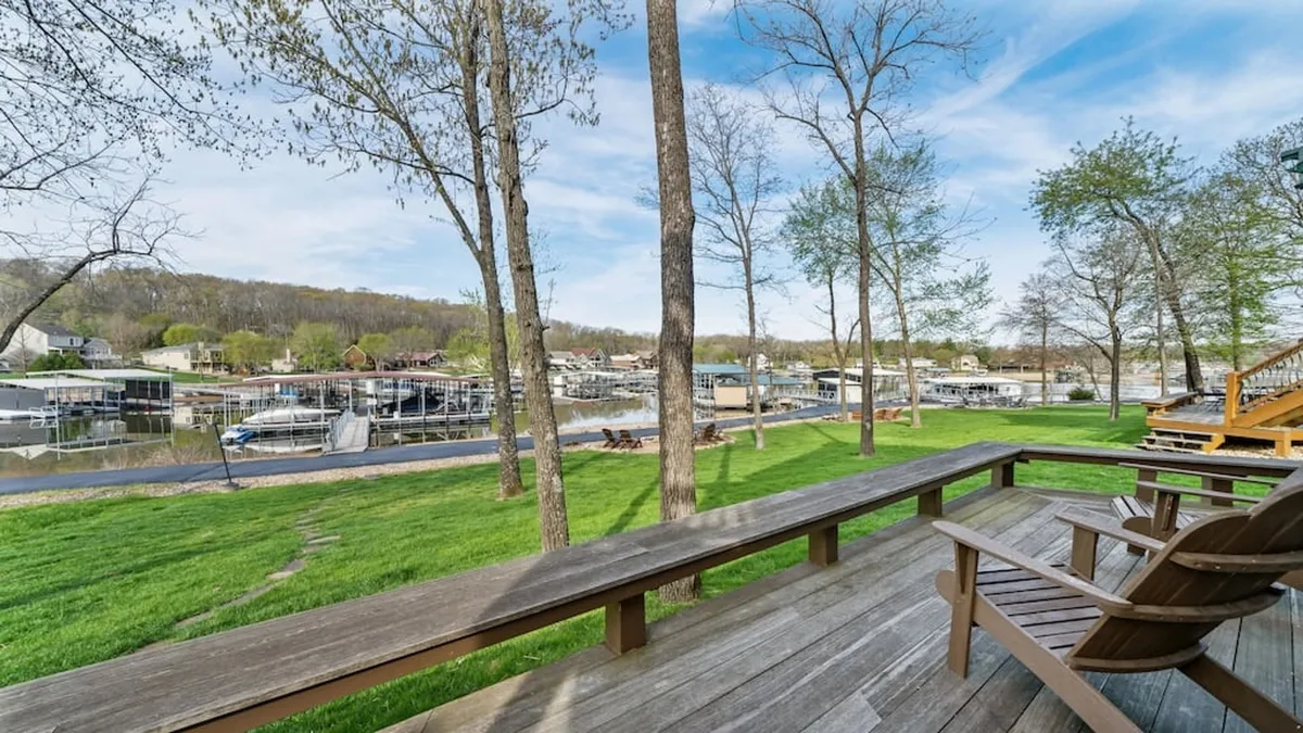 This image highlights the wooden deck overlooking the lake, with outdoor seating that invites guests to enjoy relaxing moments or meals alfresco. Boats in the marina and tree-lined shores establish the connection between indoor gathering spaces and the natural surroundings, with the deck acting as an extension of the communal heart.